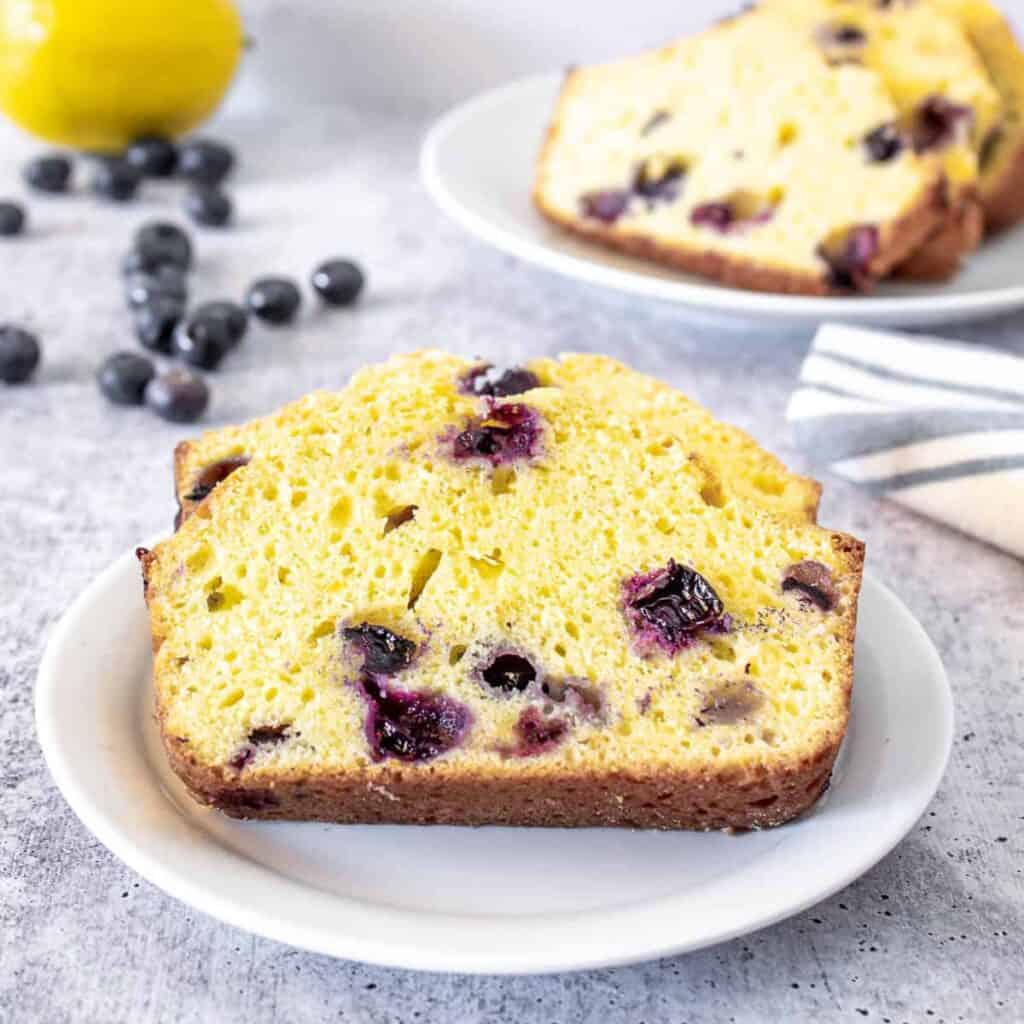 Sliced bread with blueberries on a small white plate.