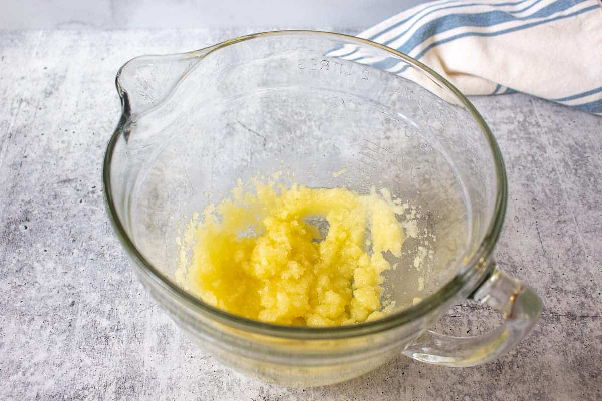 Butter and sugar combined in a glass bowl.