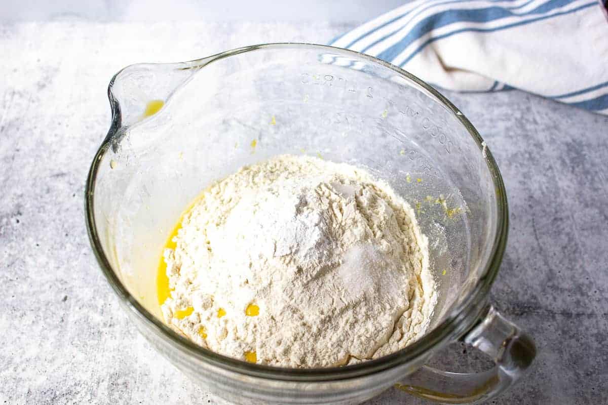 Flour added to a batter in a glass bowl.