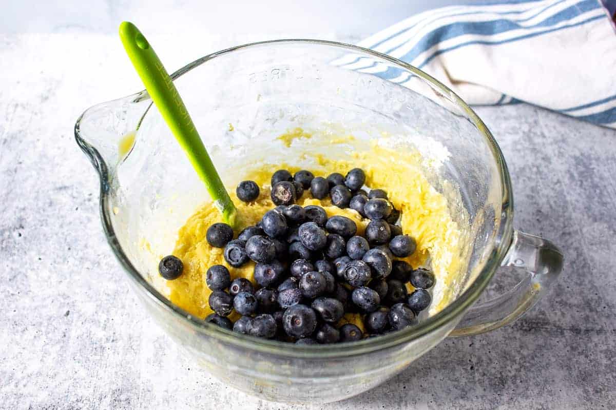 Fresh blueberries on top of a quick bread batter in a glass bowl.