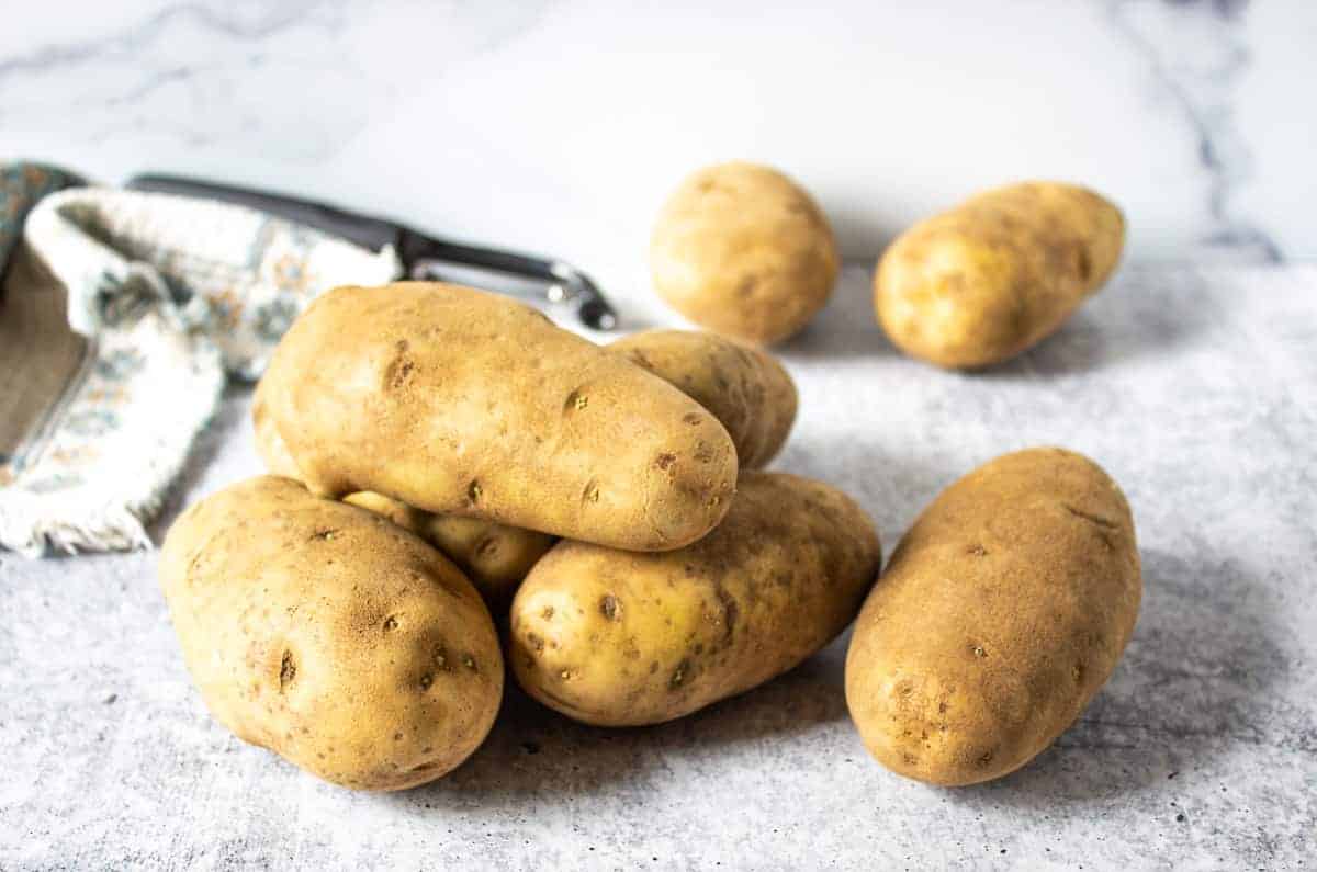 Russet potatoes piled together on a board.