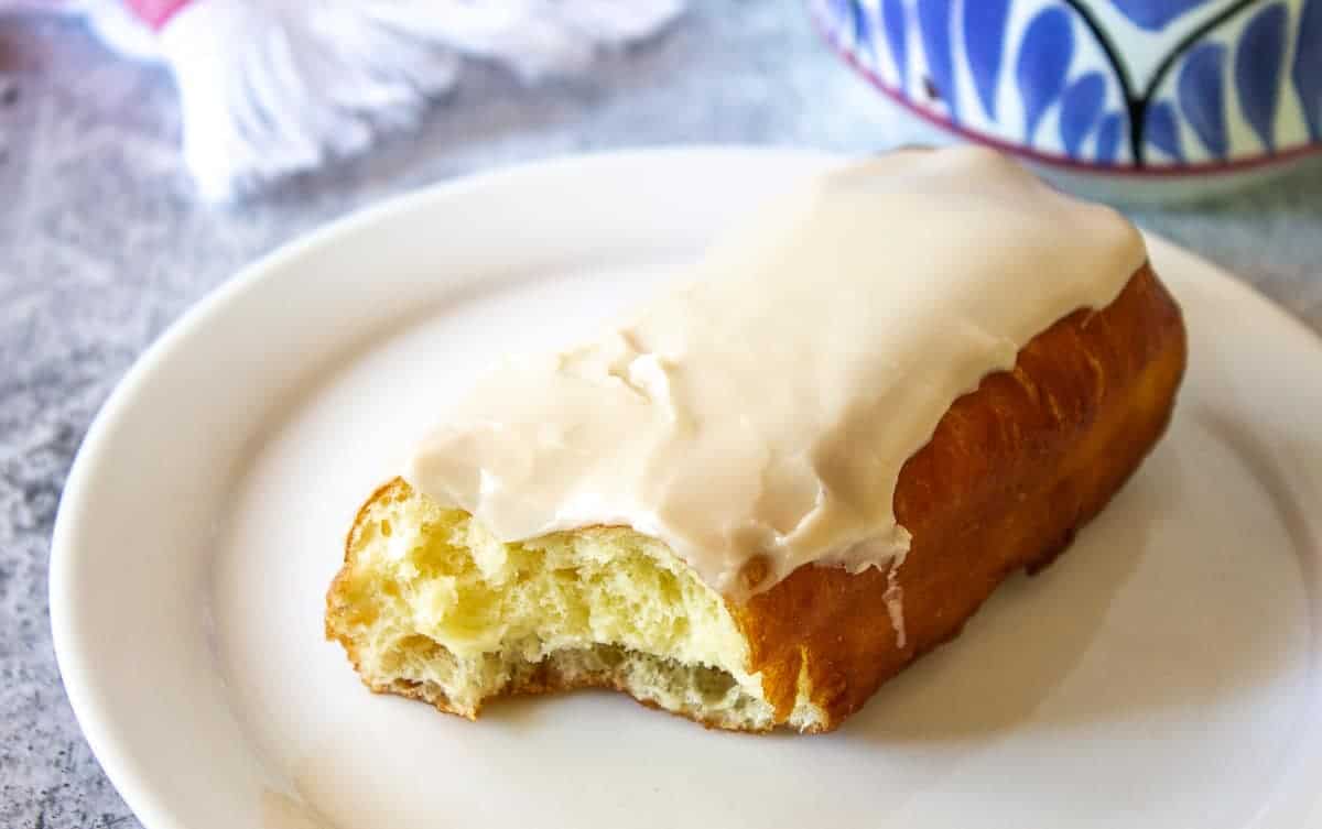 A maple bar with a bite taken out of one end.