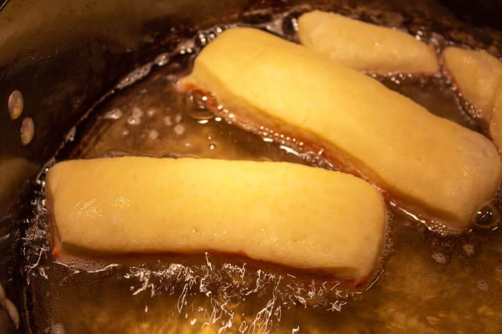 Frying maple bars in a pot of hot oil.
