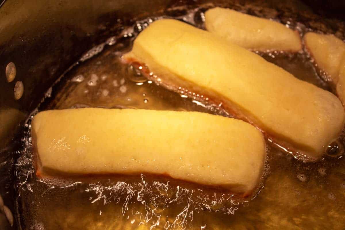 Frying maple bars in a pot of hot oil.