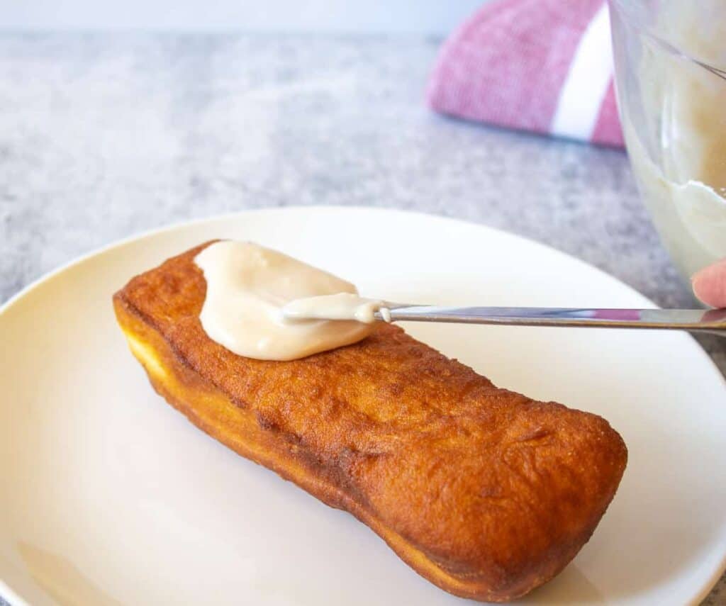 Adding frosting to a long rectangular donut.