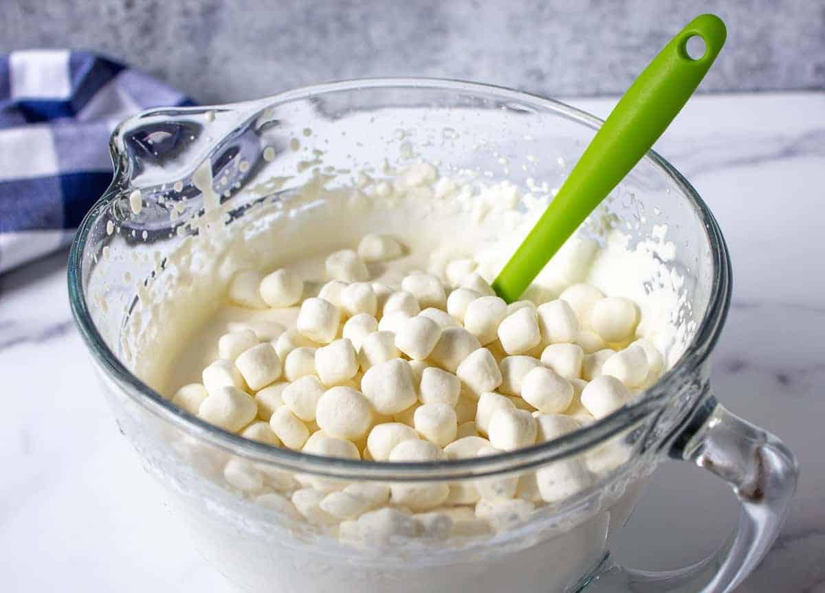 Mini marshmallows in a bowl full of whipped cream.