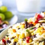 A white bowl filled with orzo, corn, beans and tomatoes.