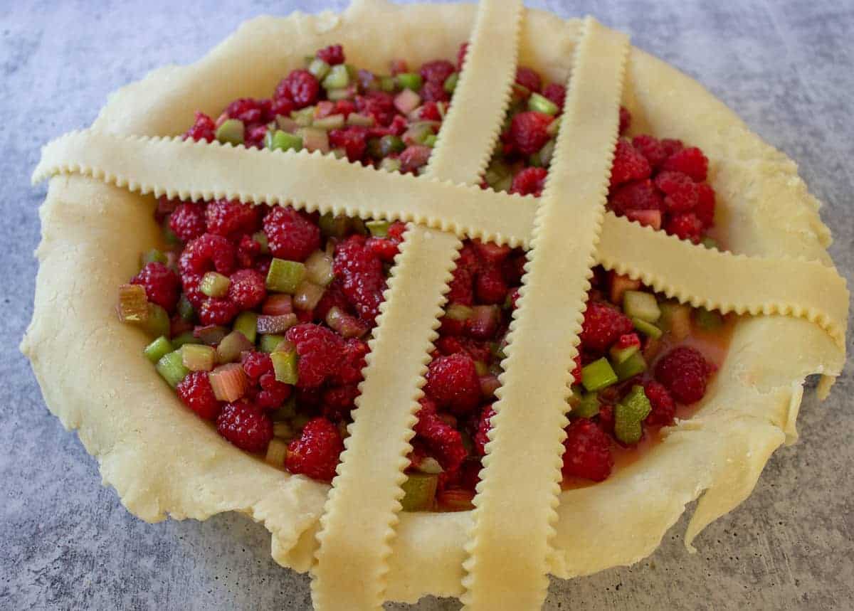 Building a top crust on a rhubarb pie with lattice strips.