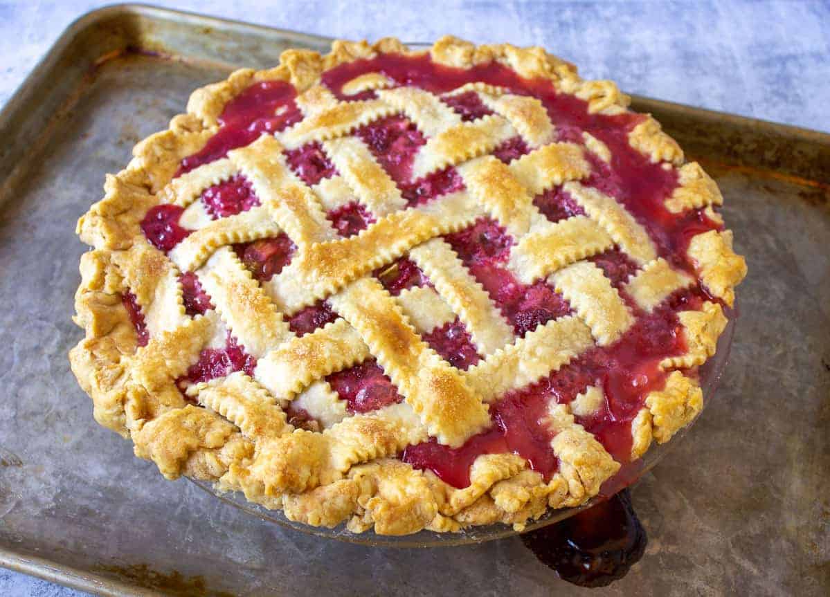 Raspberry Rhubarb Pie with a lattice crust on a baking sheet.