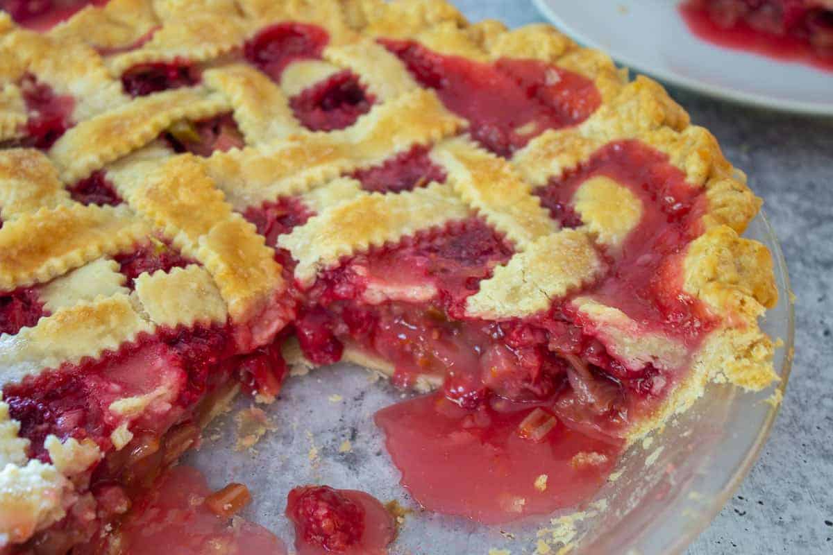 Fruit pie with a lattice crust with a few slices missing from the pie plate.