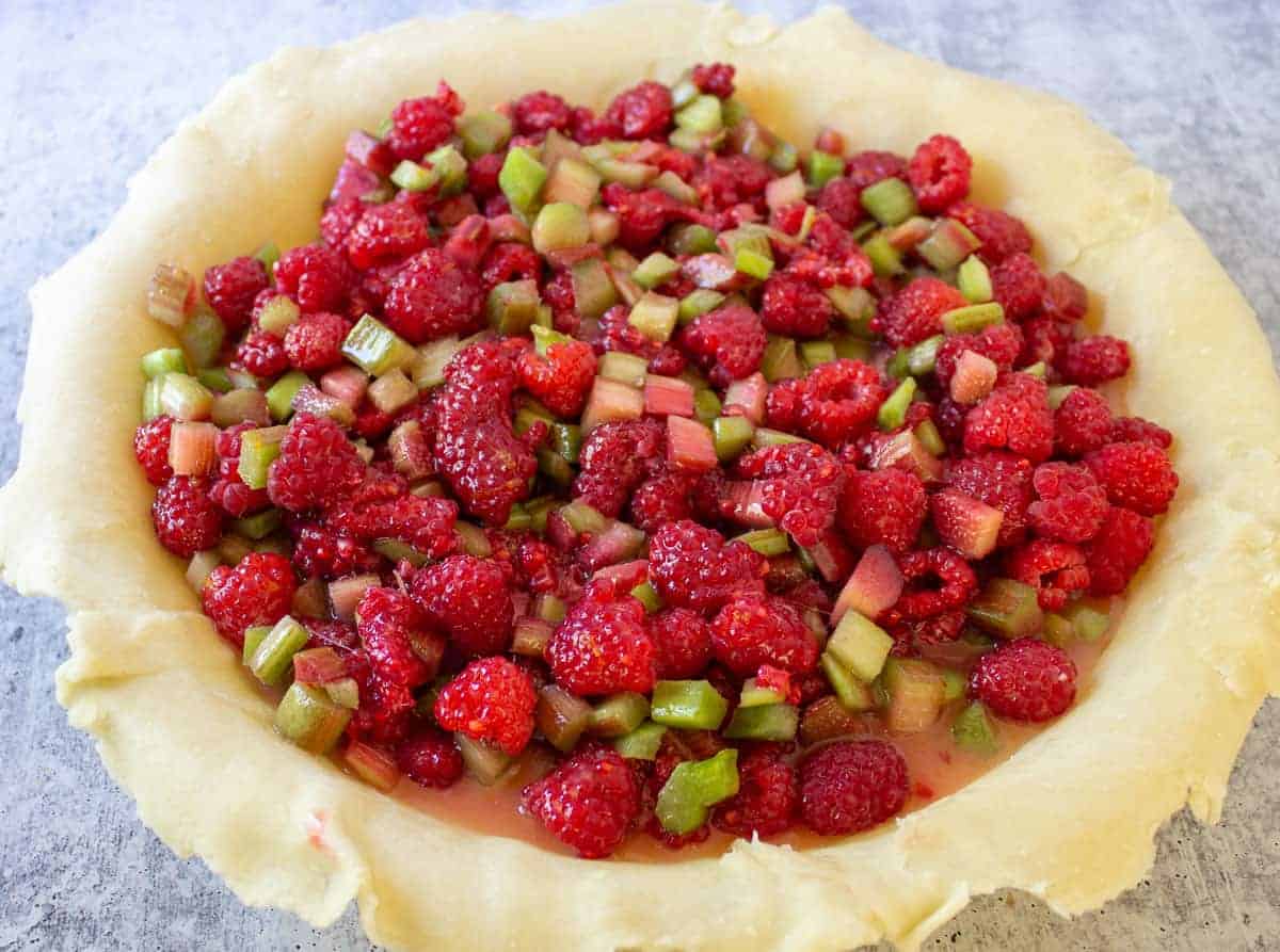 A pie crust filled with rhubarb and raspberries.