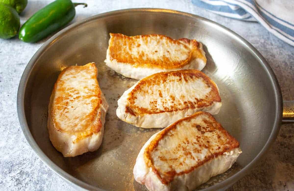 Seared pork chops in a pan.