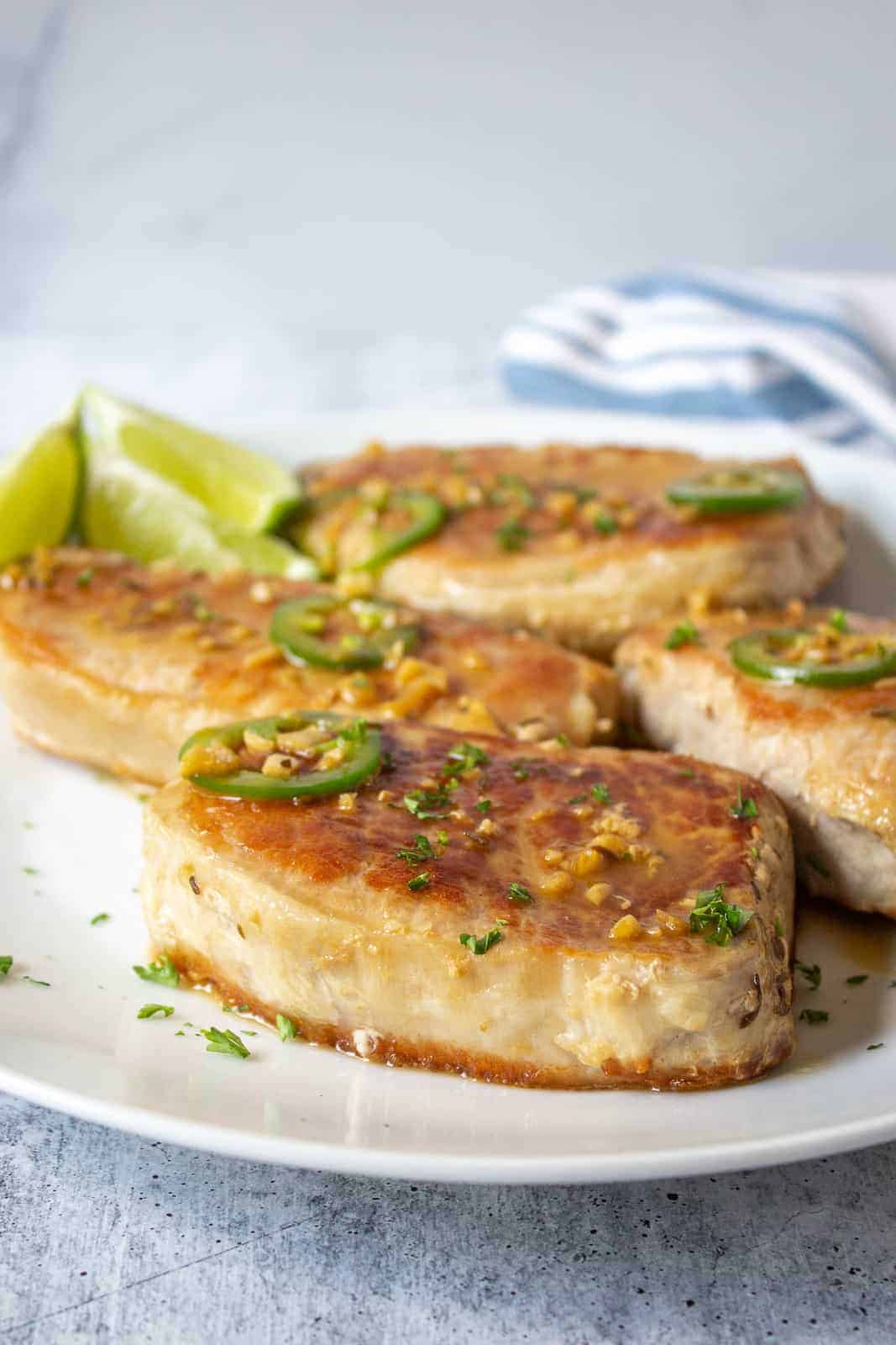 Tequila lime pork chops on a white plate with lime wedges.