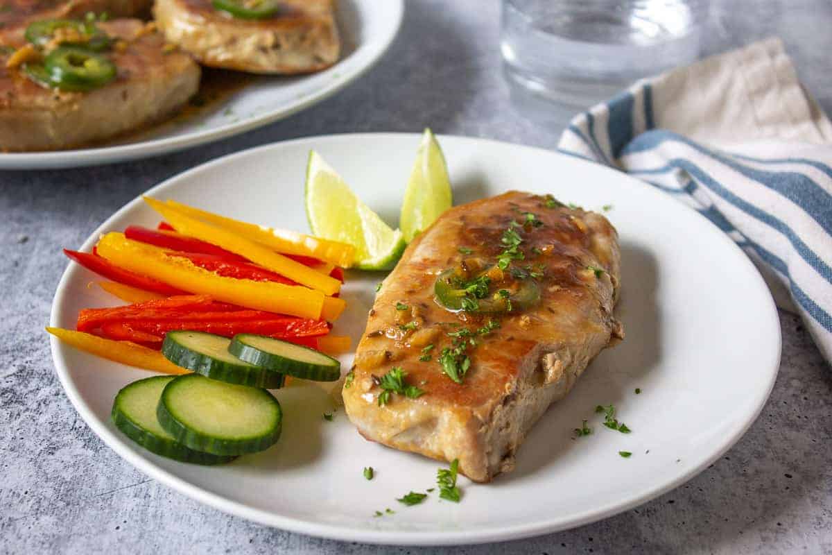 A dinner plate with a pork chop and fresh veggies.