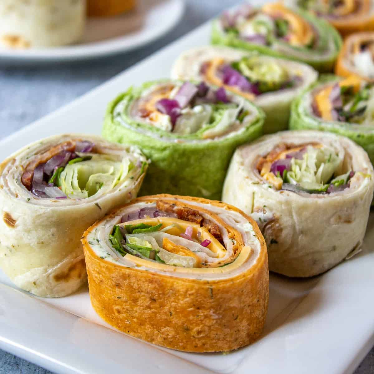 Sliced turkey wraps in different colors on a white plate.