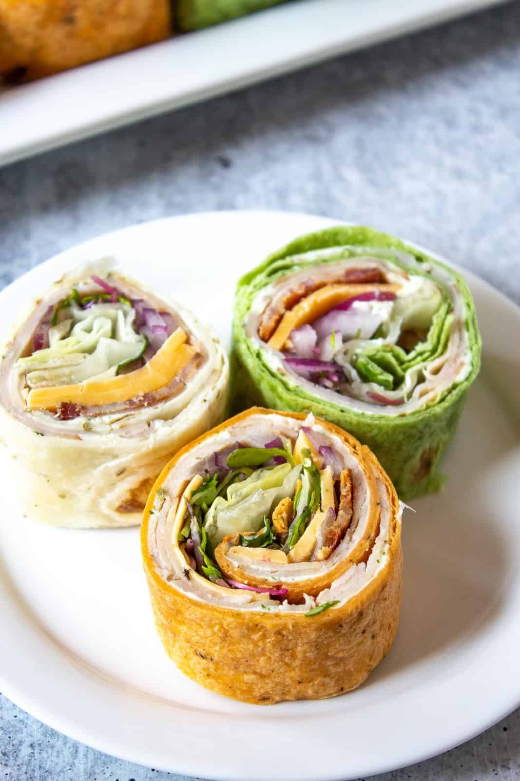 Turkey wraps cut into small rounds on a white plate.