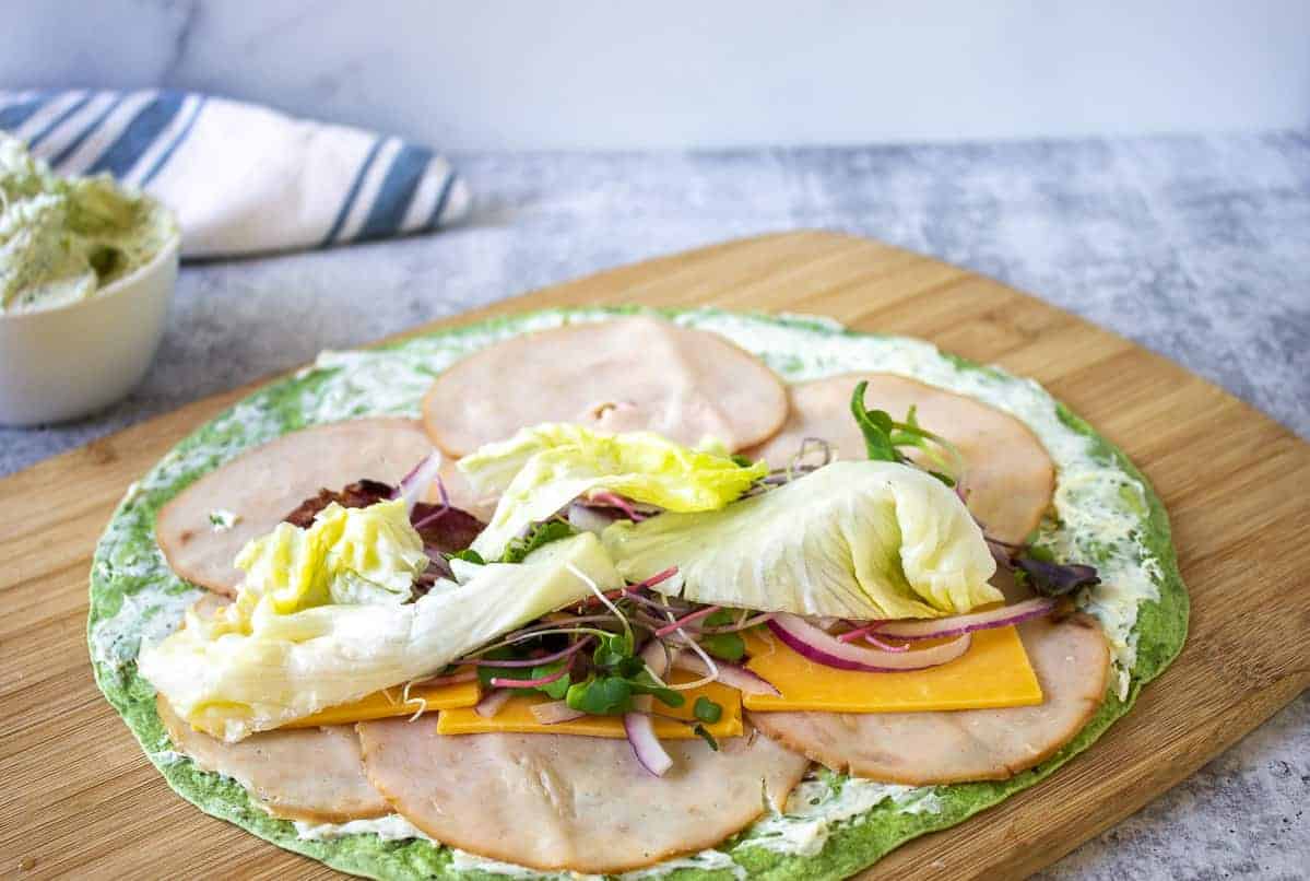 Lettuce added on top of a sandwich wrap.