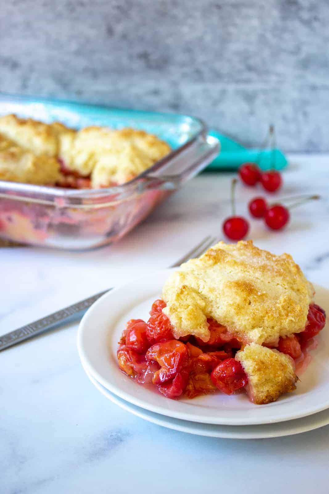 Cherry cobbler on a plate and in a casserole dish.