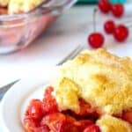 Cherry cobbler with a biscuit topping on a white plate.