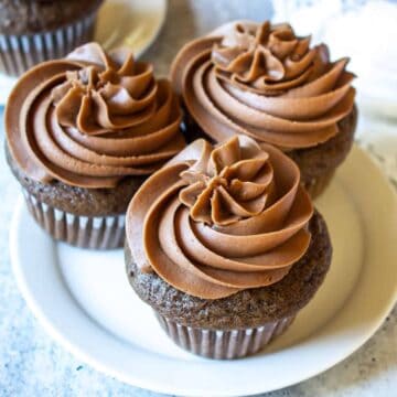 Three chocolate cupcakes topped with swirled chocolate buttercream.