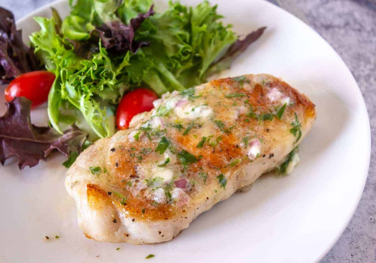 Melted compound butter with herbs and shallots on a pork chop.