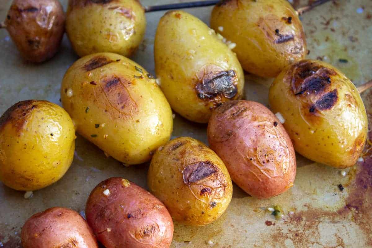 Cooked red and yellow potatoes on a baking sheet.