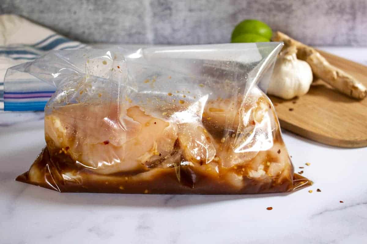 Chicken breasts in a plastic bag with a marinade.