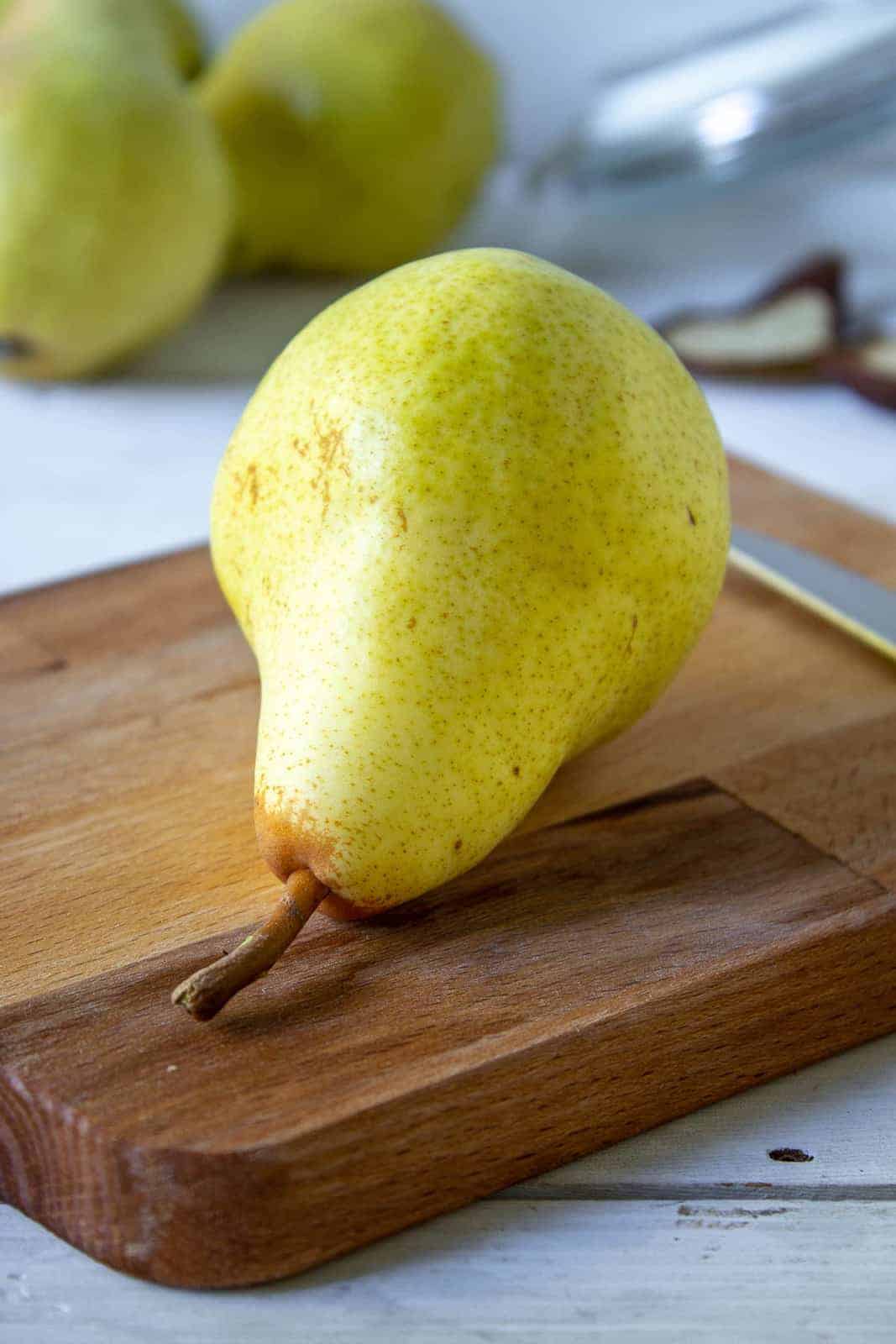 A fresh pear on a wooden cutting board.