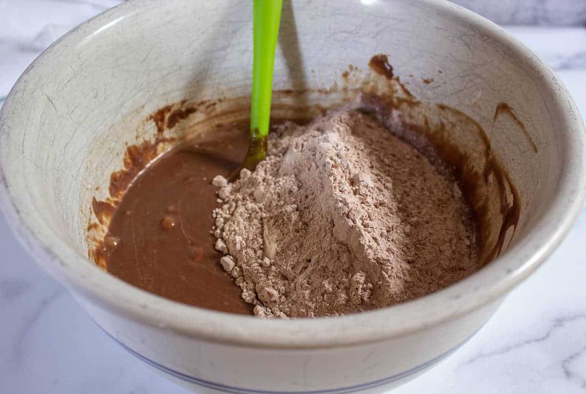 Flour mixture on top of a chocolate batter in a large bowl.