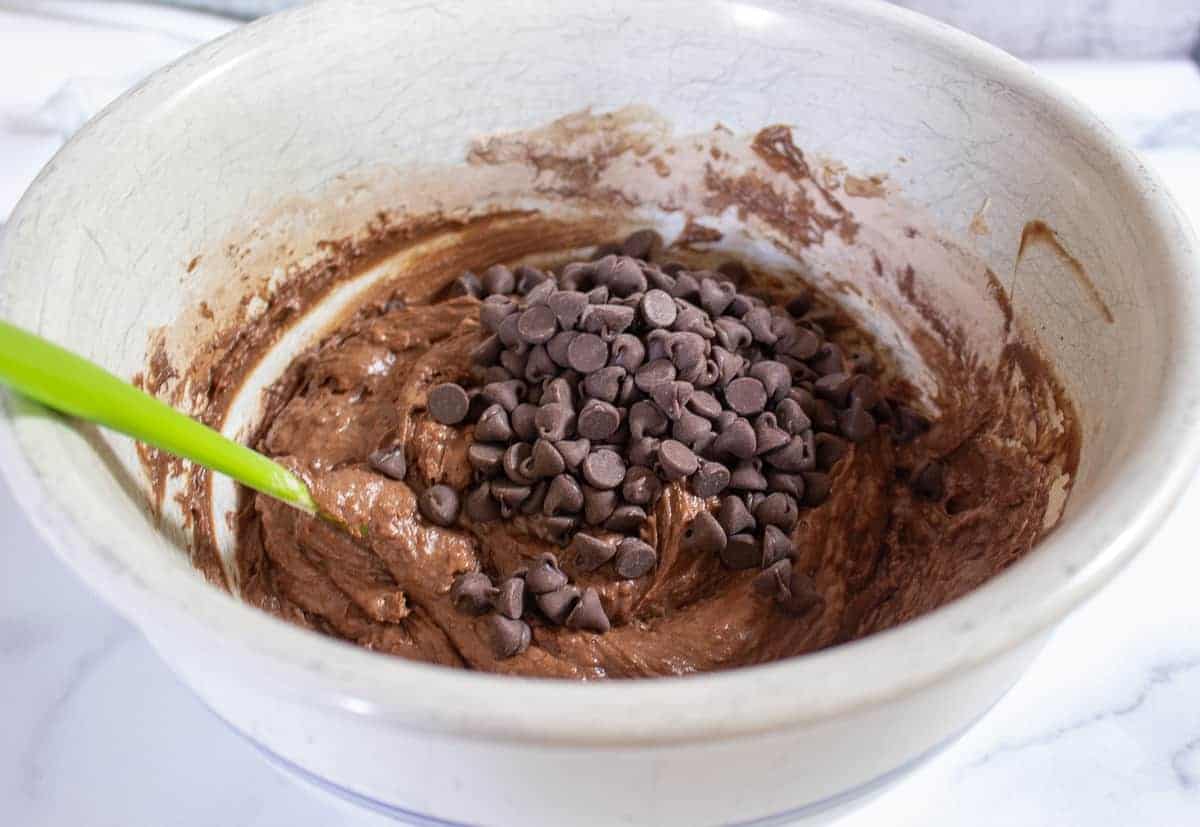 Chocolate chips added to a bowl of chocolate muffin batter.