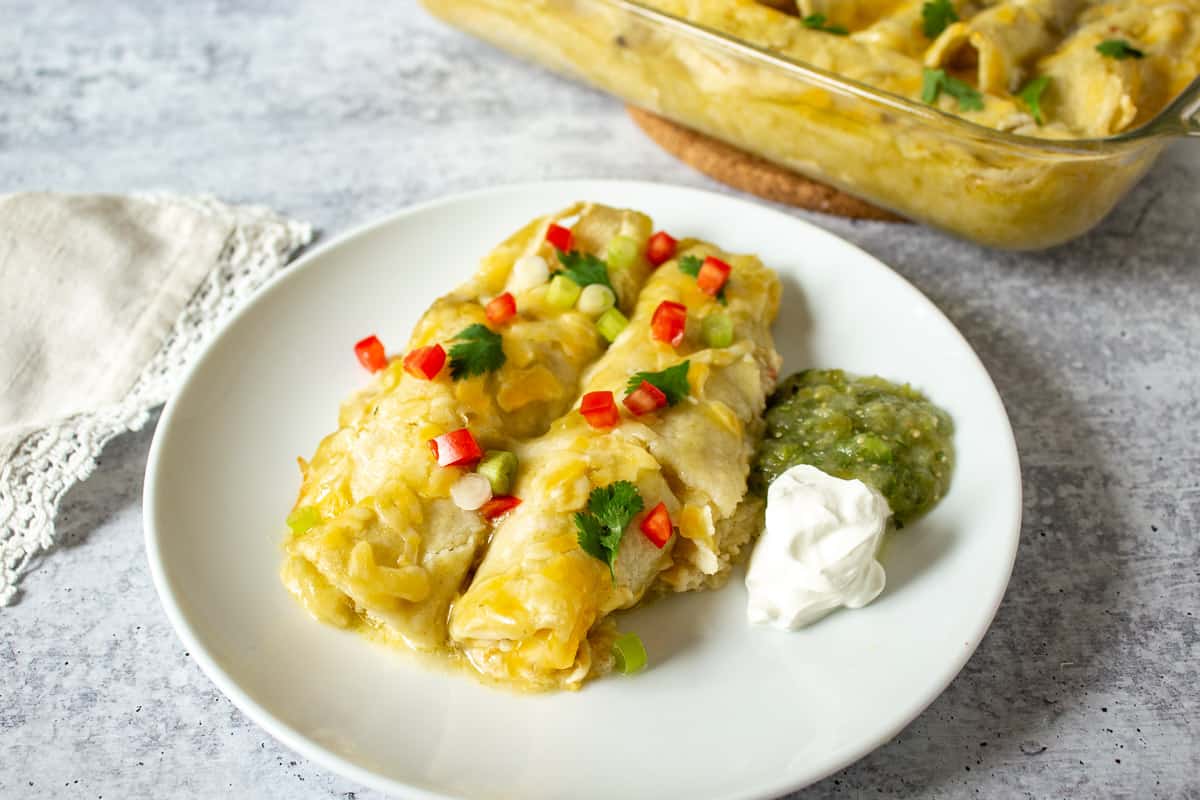 Chicken enchiladas topped with chopped tomatoes and cheese.