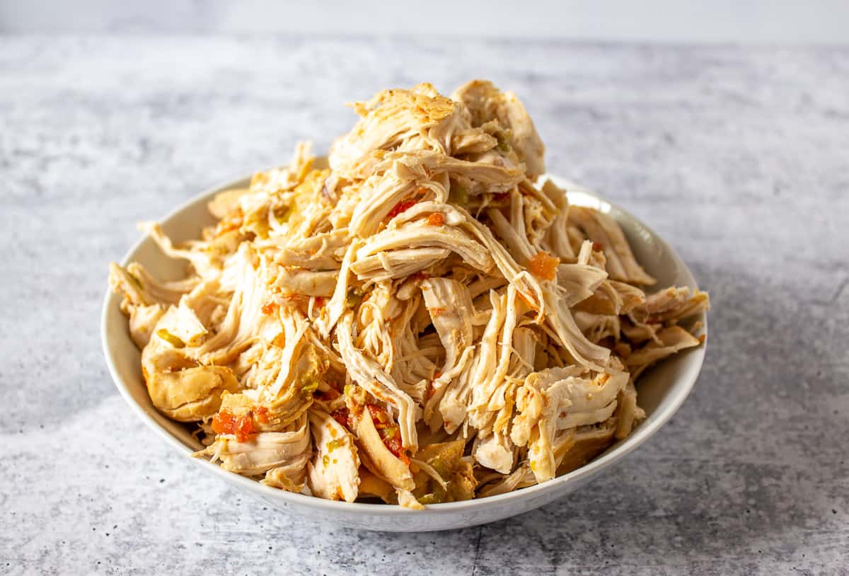 A pile of shredded chicken in a white bowl.