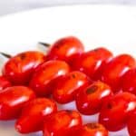 Cherry tomatoes on a wooden skewer with black grill marks on the tomatoes.