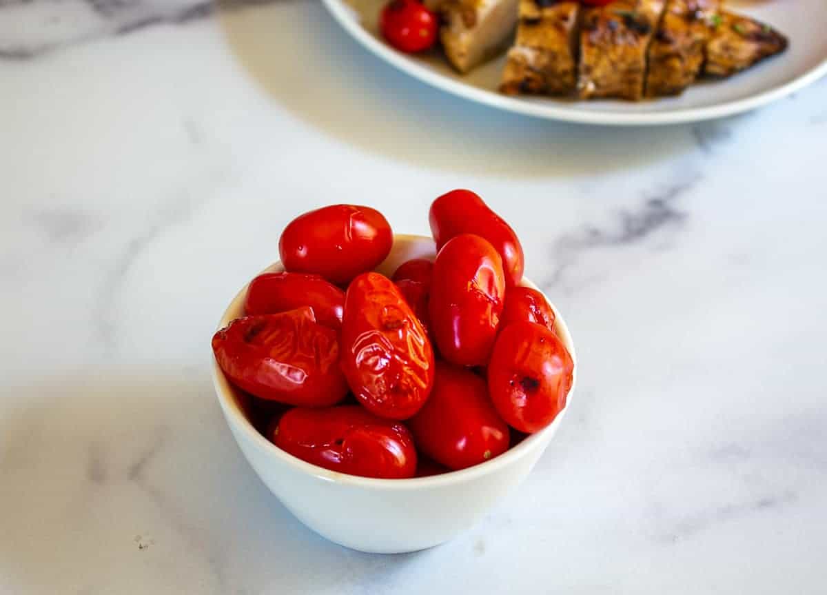 Grilled cherry tomatoes in a small white bowl.