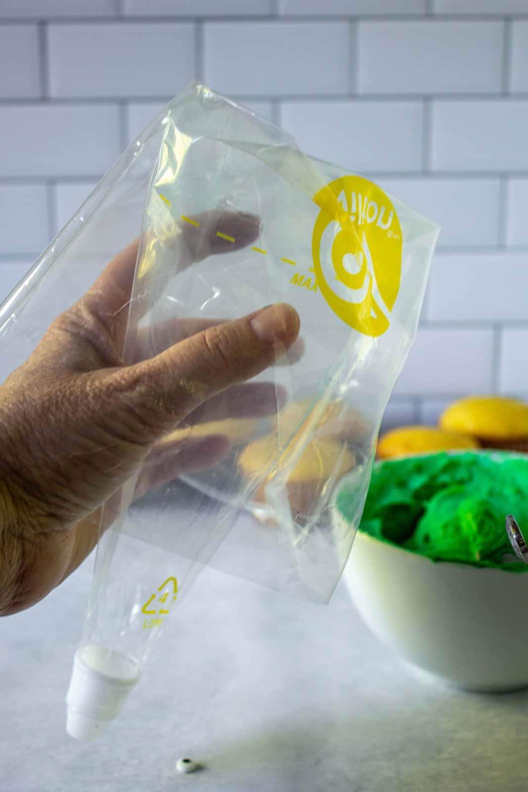 A plastic decorating bag folder over a hand. 