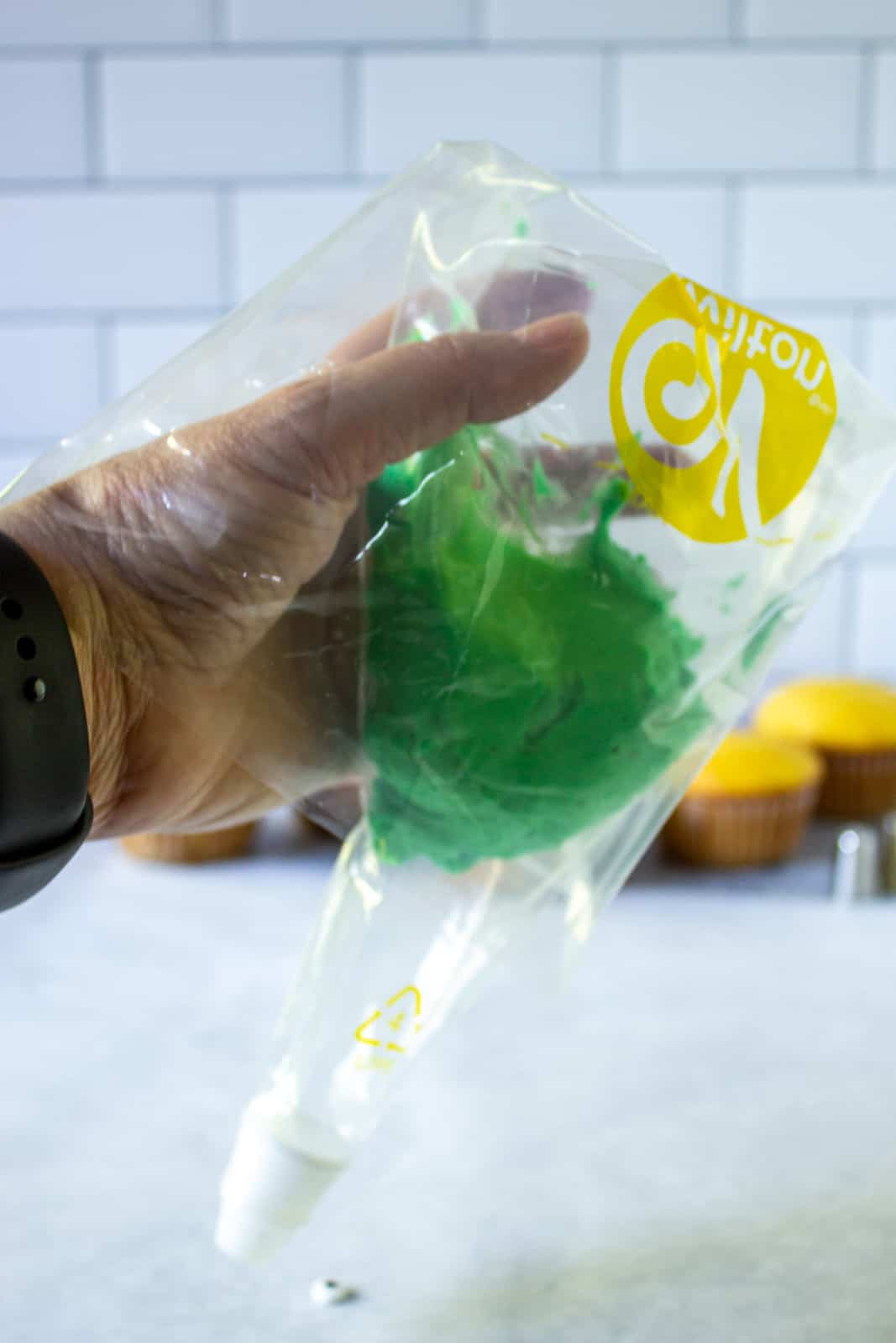 A cake decorating bag being filled with green frosting. 