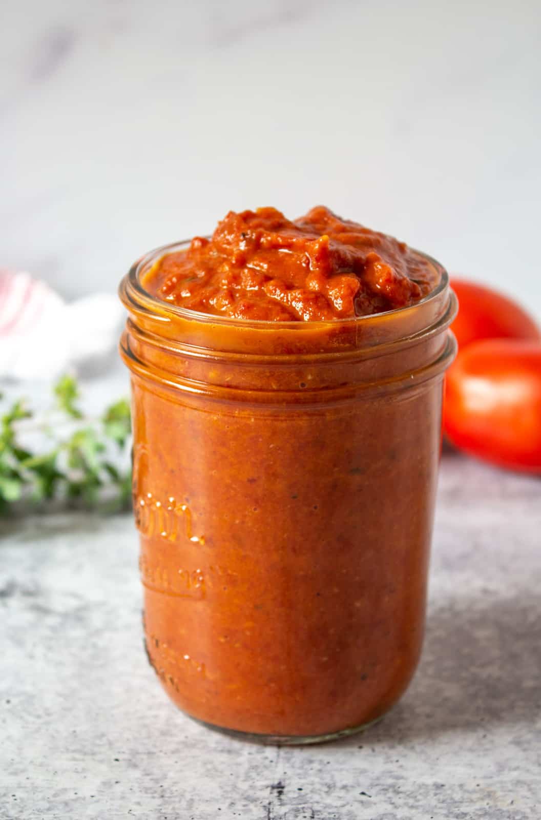 A mason jar filled with a marinara sauce.