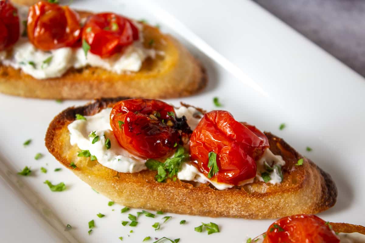 Roasted cherry tomatoes on grilled toast with creamy cheese.