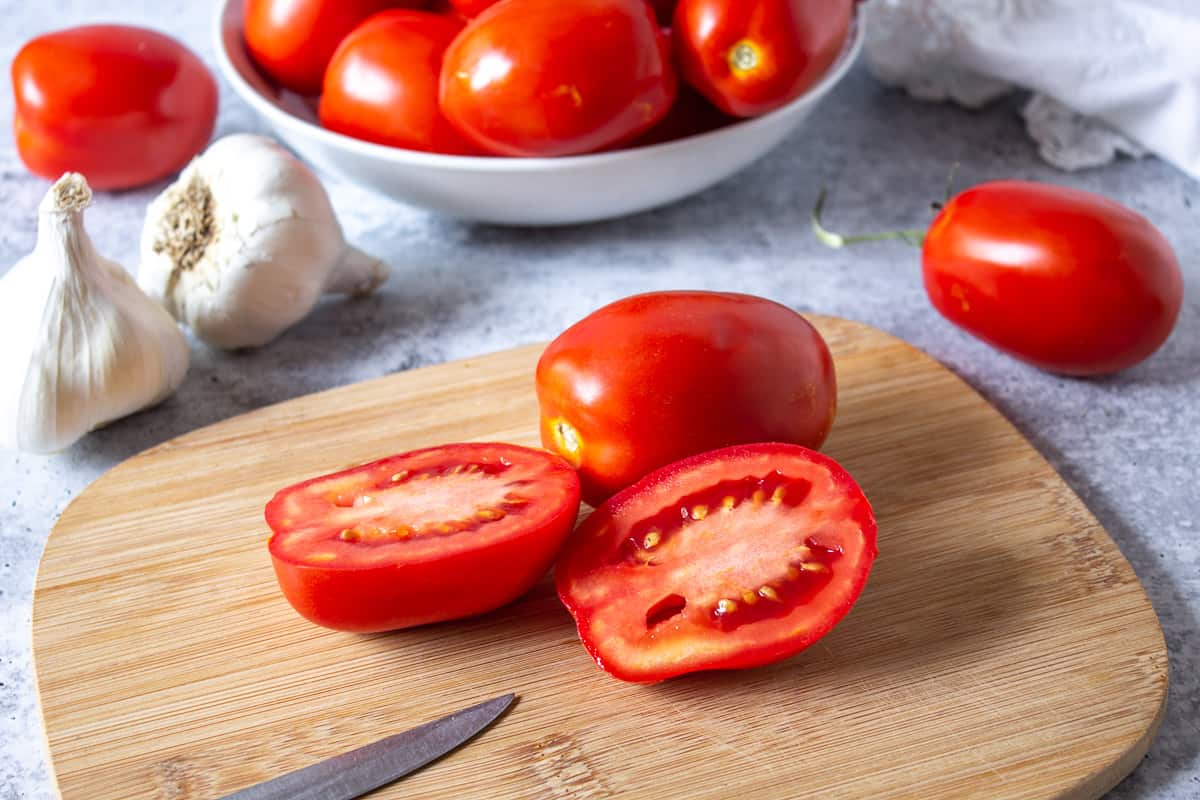 Roma tomatoes sliced in half on a cutting board. 