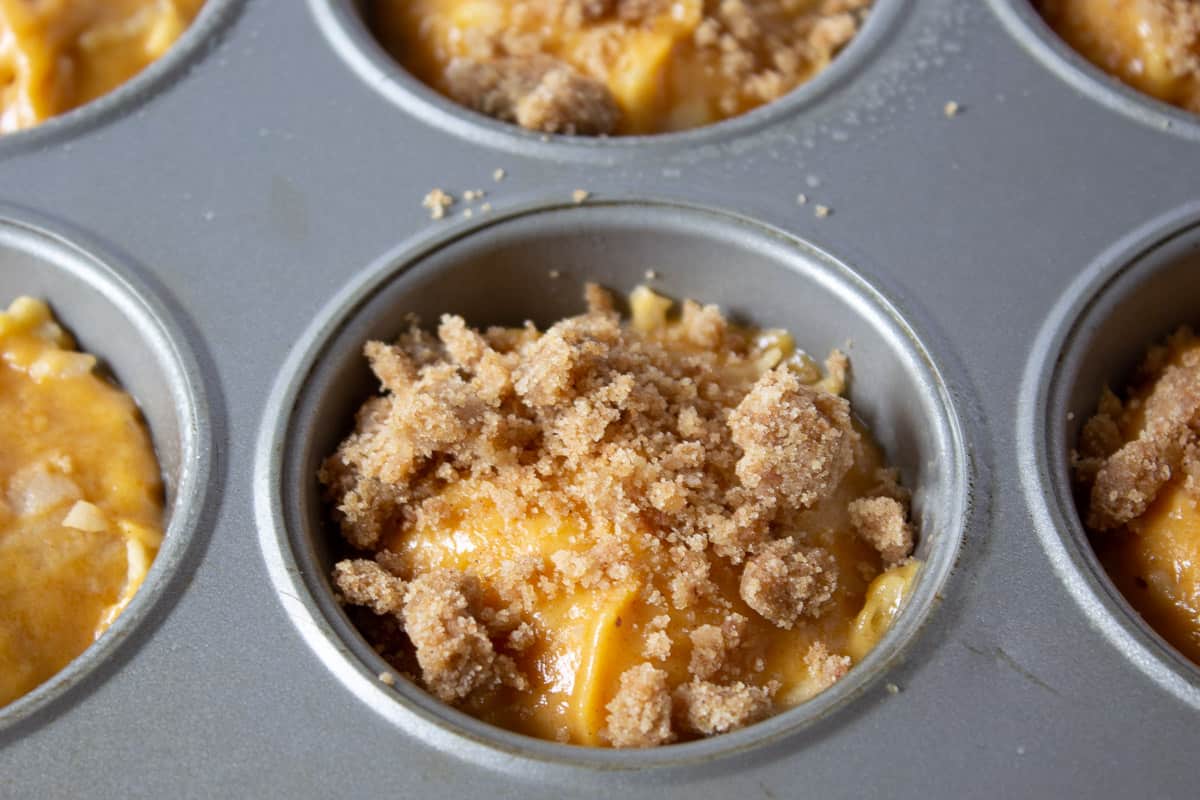 Muffin batter topped with a struesel topping in a muffin tin.