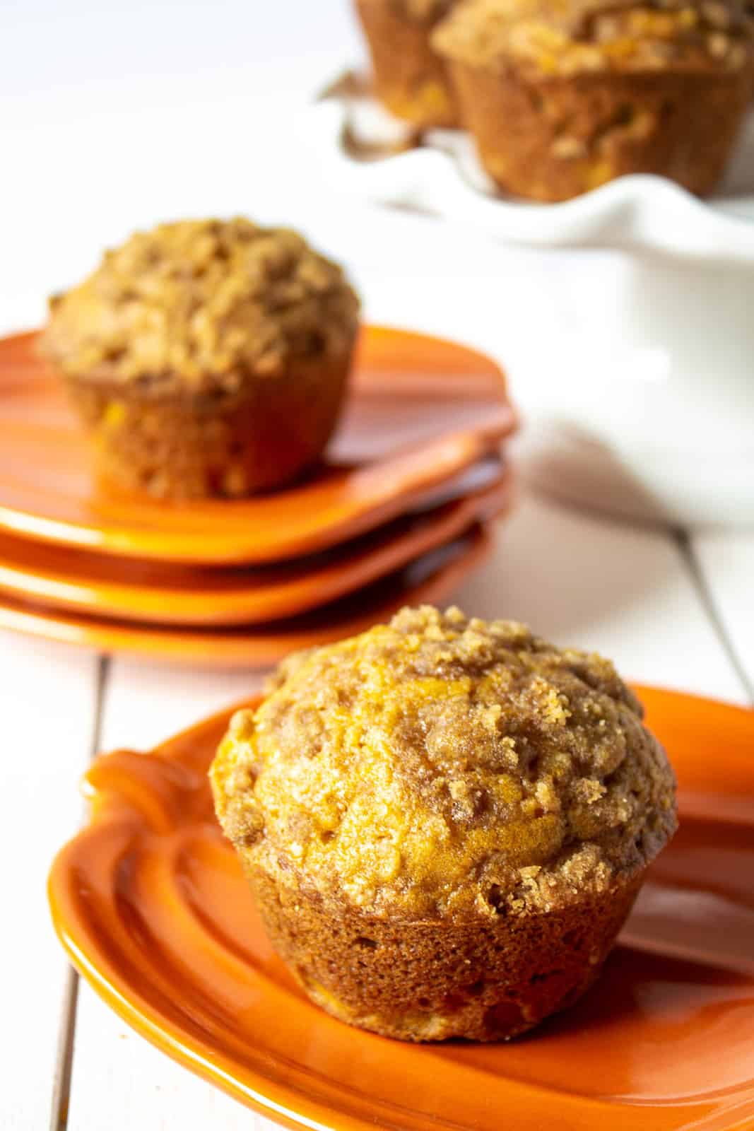 A pumpkin muffin on an orange pumpkin shaped plate.