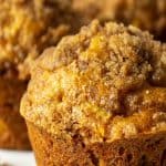 A pumpkin apple muffin on a white scalloped plate.