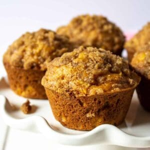 Pumpkin muffins with a streusel topping on a white cake stand.topping