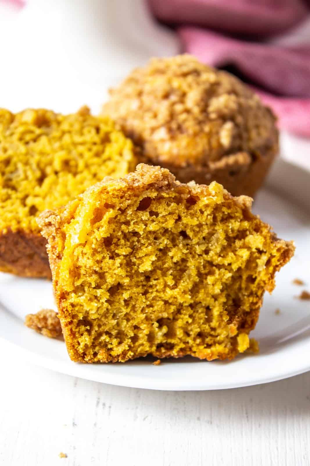 A pumpkin muffin cut in half on a white plate.