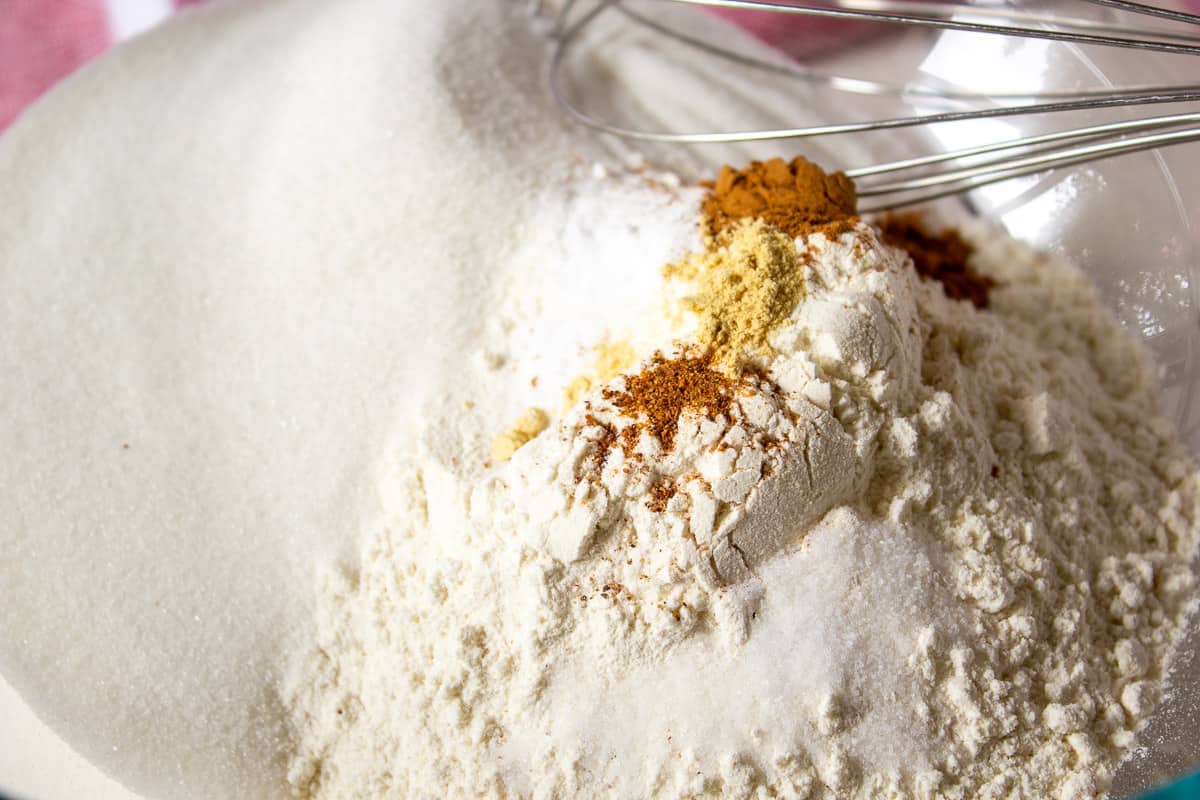 Flour and spices in a mixing bowl with a wire whisk.