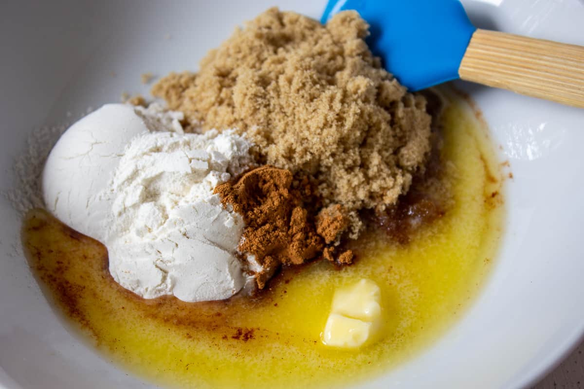 Brown sugar with melted butter and flour in a white bowl.