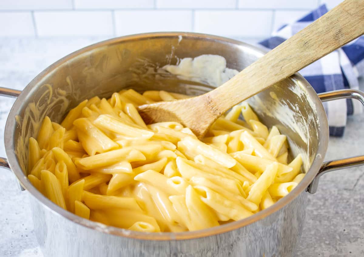 Macaroni and cheese in a sauce pot with a wooden spoon.