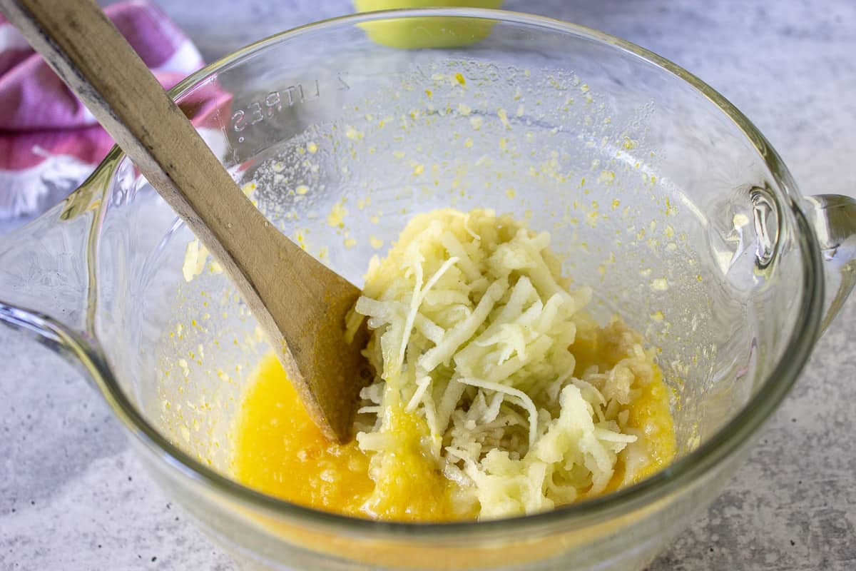 Eggs, butter and sugar combined together with grated apples on top of mixture.