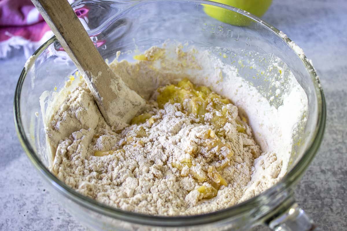 Flour mixture added to a wet mixture in a glass bowl.