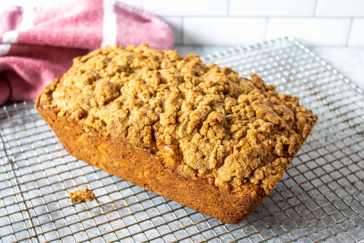 A loaf of bread topped with a crumble topping on a baking rack. 